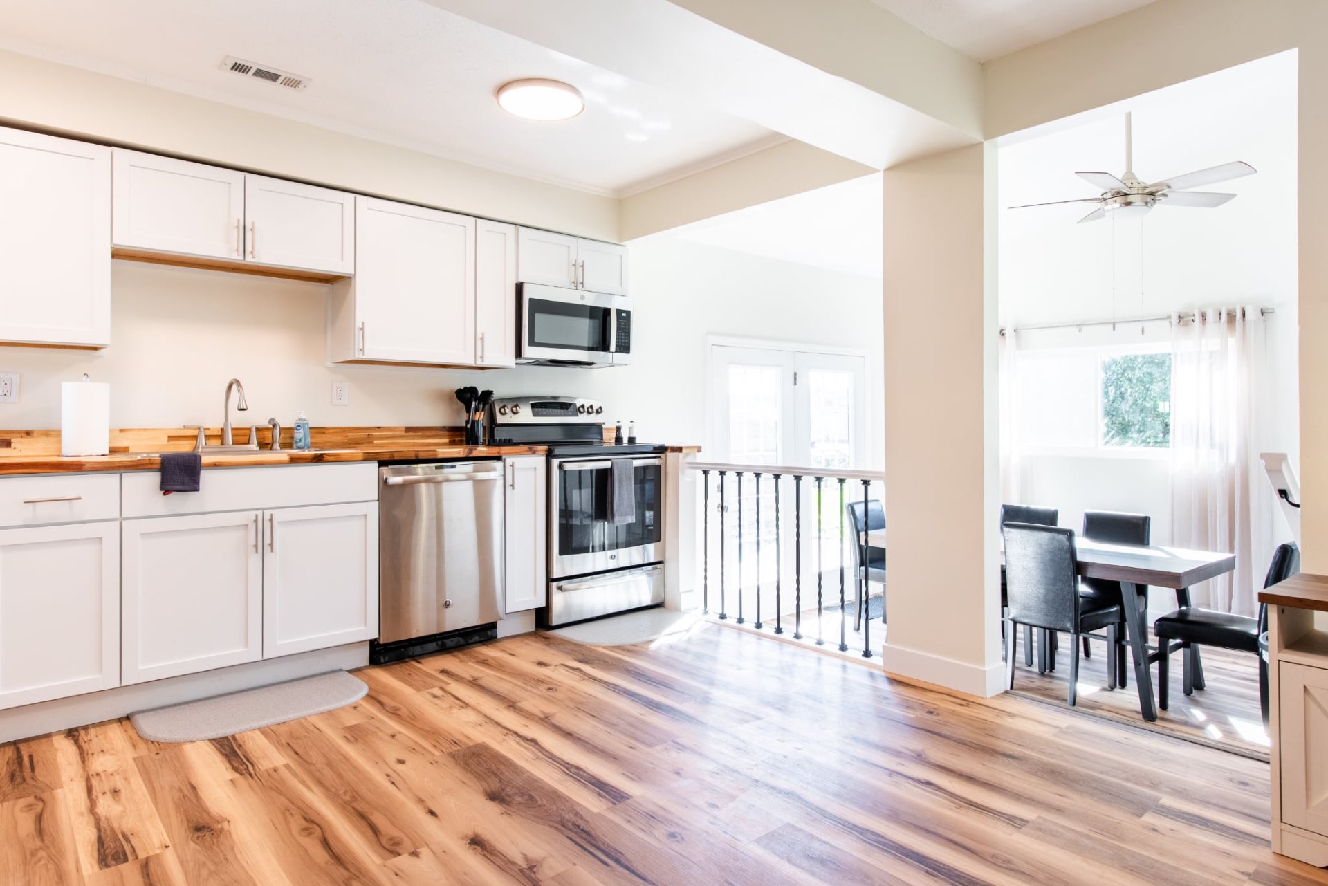 Open kitchen with white cabinets, wood floors, and adjoining dining space