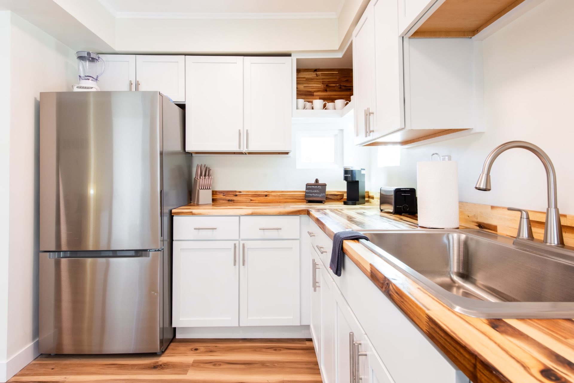Kitchen with full-size refrigerator, white cabinets, and wood countertops