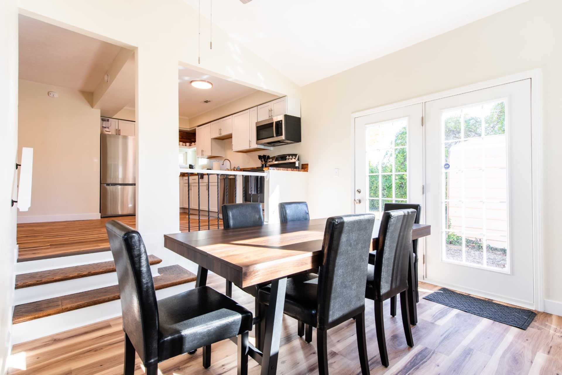 Dining table and chairs beside sunlit French doors