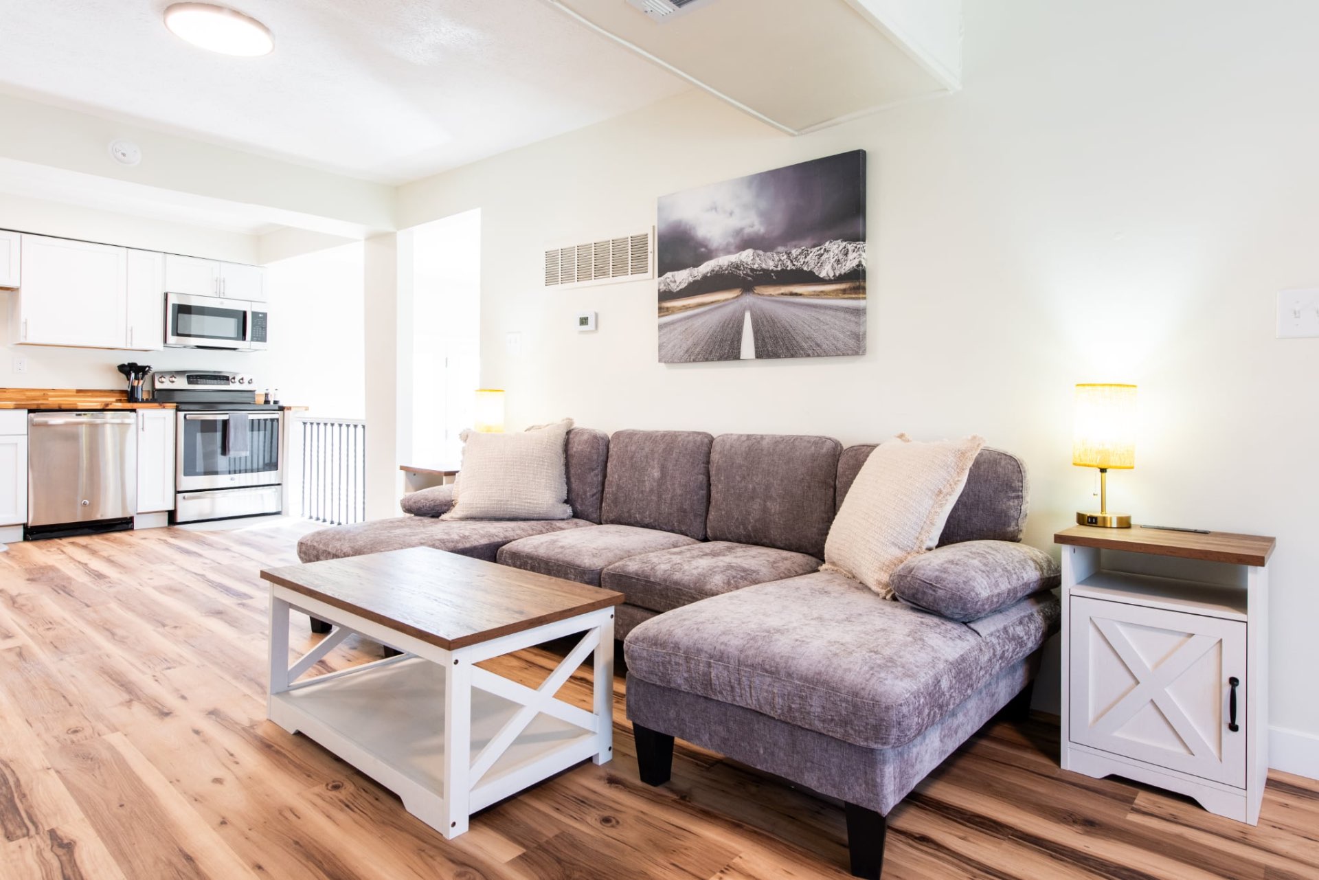 Bright shared living room with a sectional sofa and adjoining kitchen